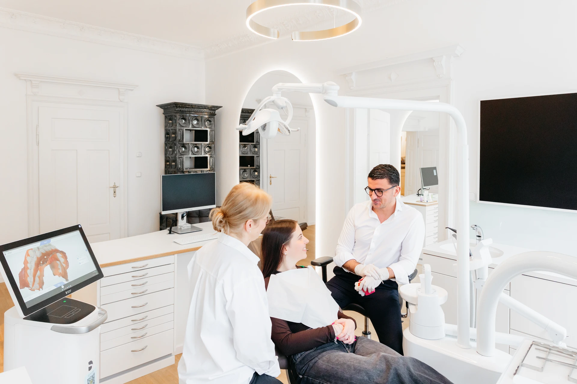 zahnarzt-oberholzer_schwabing_beratungsgespraech-behandlungsraum Beratungsgespräch zwischen Zahnarzt-Team und Patientin im Behandlungsraum der Praxis Dr. Oberholzer Schwabing