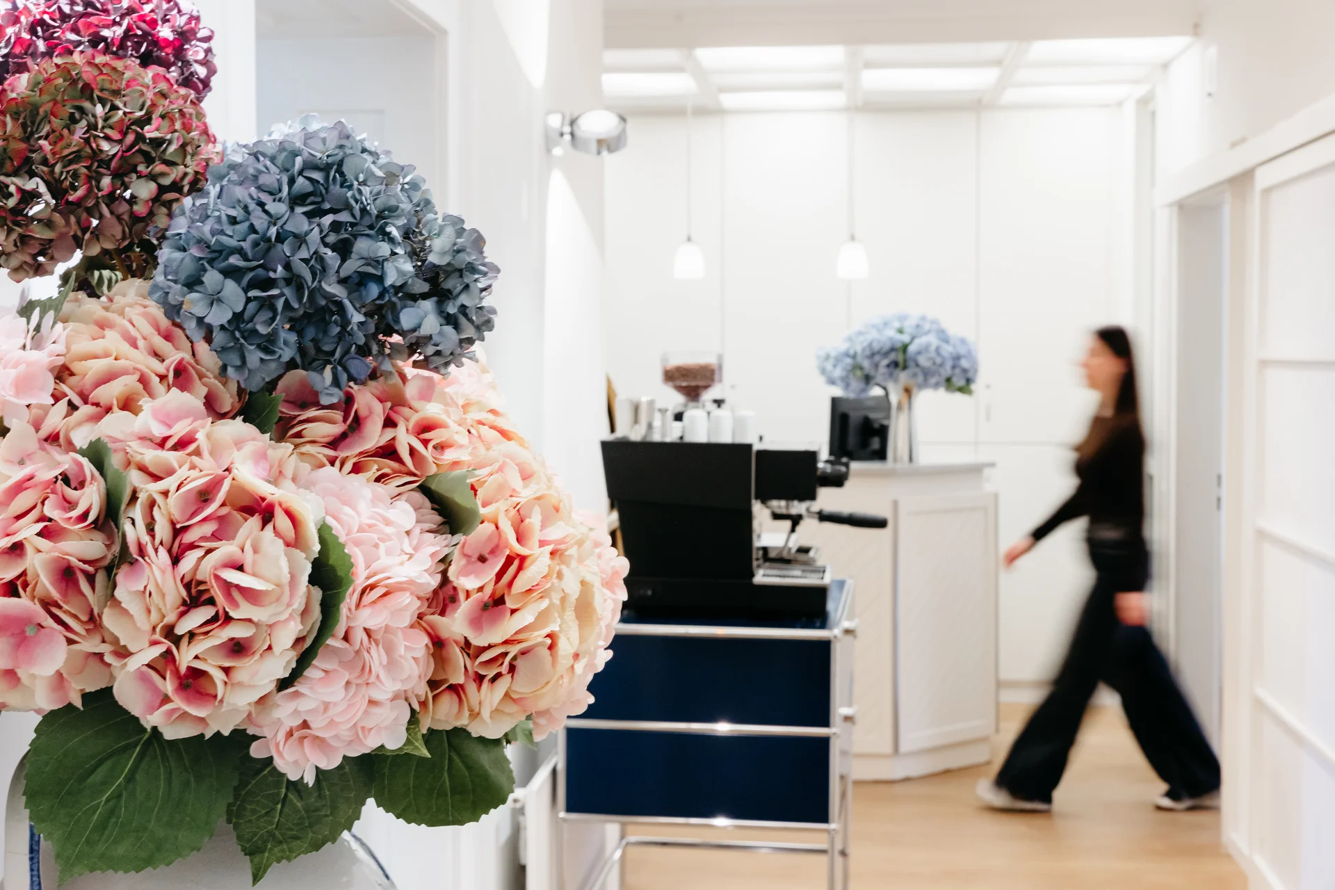 zahnarzt-oberholzer_schwabing_empfangsbereich-blumen Empfangsbereich mit Hortensien-Blumenarrangement und Kaffeebar in der Zahnarztpraxis Dr. Oberholzer Schwabing