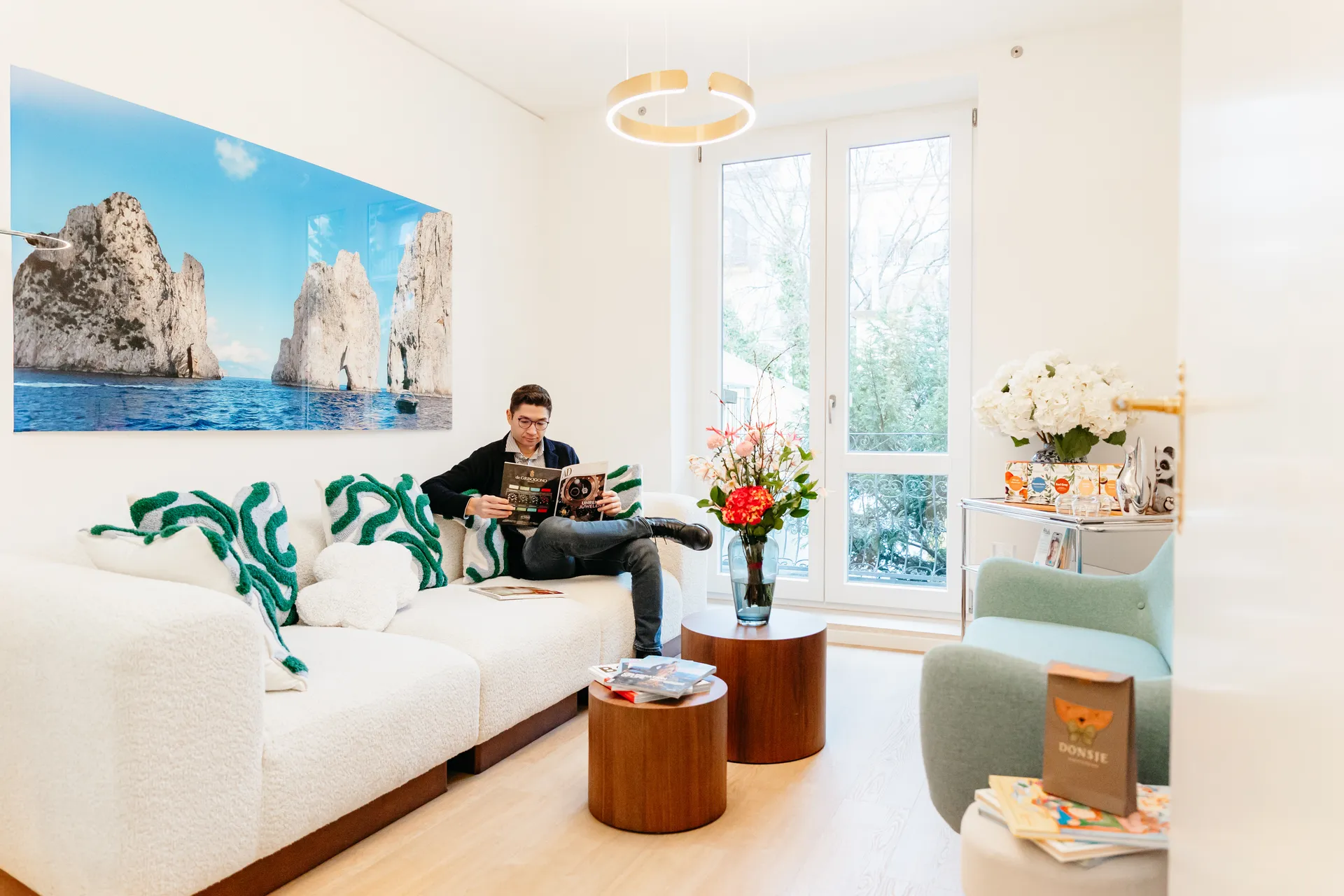 zahnarzt-oberholzer_schwabing_wartebereich-lounge Gemütlicher Wartebereich mit Sofa und Meerblick-Kunstwerk in der Zahnarztpraxis Dr. Oberholzer München Schwabing